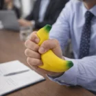 Businessperson squeezing Stress Toys Banana for stress relief at a meeting table.