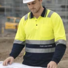 Construction worker in hard hat reviews blueprints wearing Mens TrueDry Long Sleeve Safety Shirt.