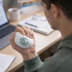 Person squeezing a Jace Volleyballs Stress Toy for stress relief while working at a desk.