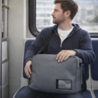 Man on public transport with a gray Ventura Satchels bag looks out the window.