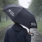 Person holding an Umbrellas Inverted while walking in the rain on a tree-lined path.