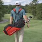 Man carrying a Taylormade Flextech Red Black Stand Bag on a golf course.