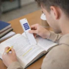 Man studying with a pencil and a White 15Cm PVC Bookmark / Ruler in an open book at his desk.