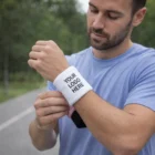 Man outdoors putting on a Y-002 Wristbands Big with "YOUR LOGO HERE" text.