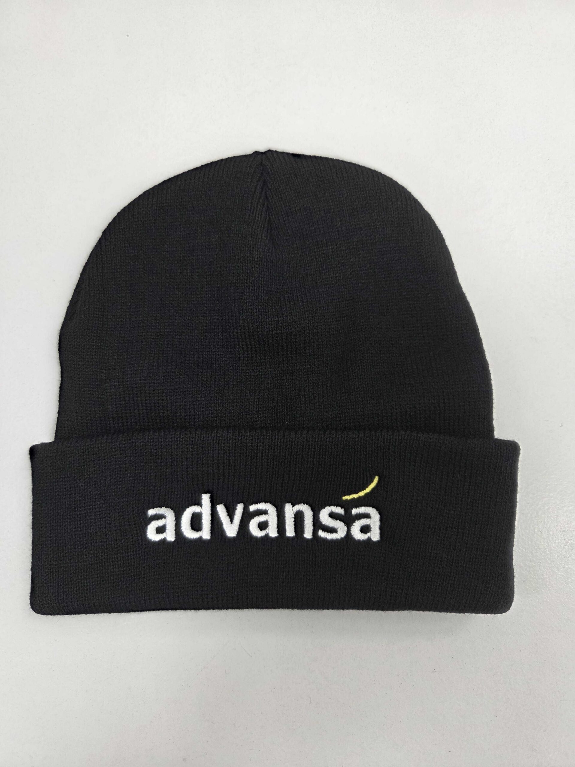 Black beanie with Advansa embroidered in white and a yellow curved line above the a. Happy Client!.