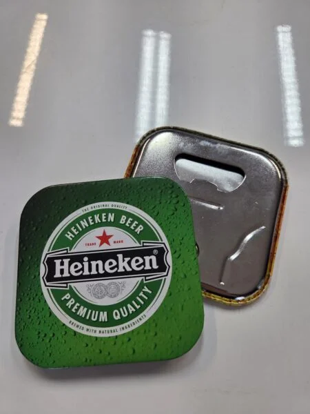 A Heineken-branded metal bottle opener, perfect for conference merchandise, on a white surface.