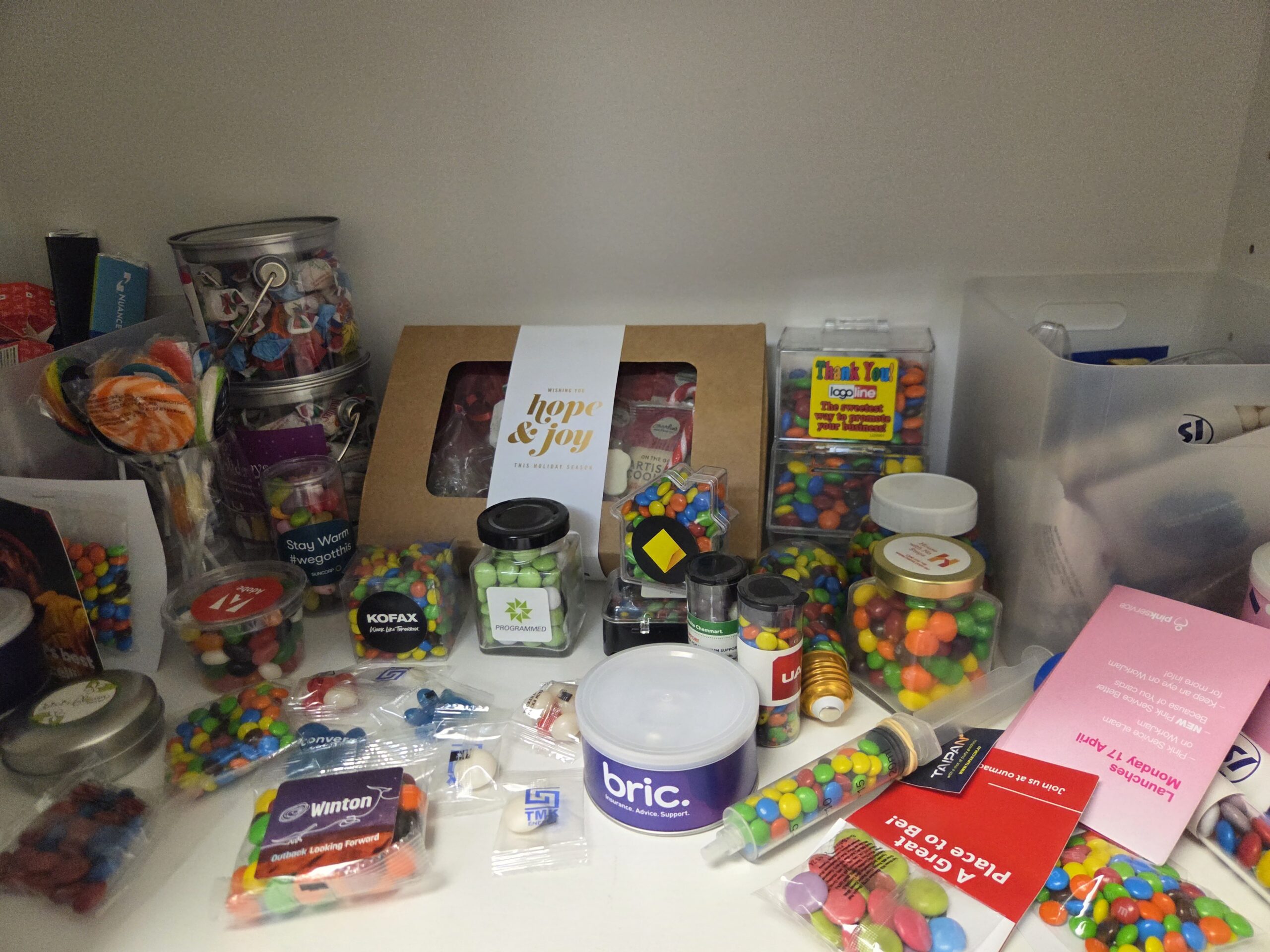 A shelf filled with colorful candies, sweets, and treats alongside fun branded merch samples.