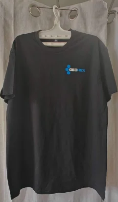 Black T-shirt with a small blue and white GEOHEX logo by Holloway Group, on a hanger.