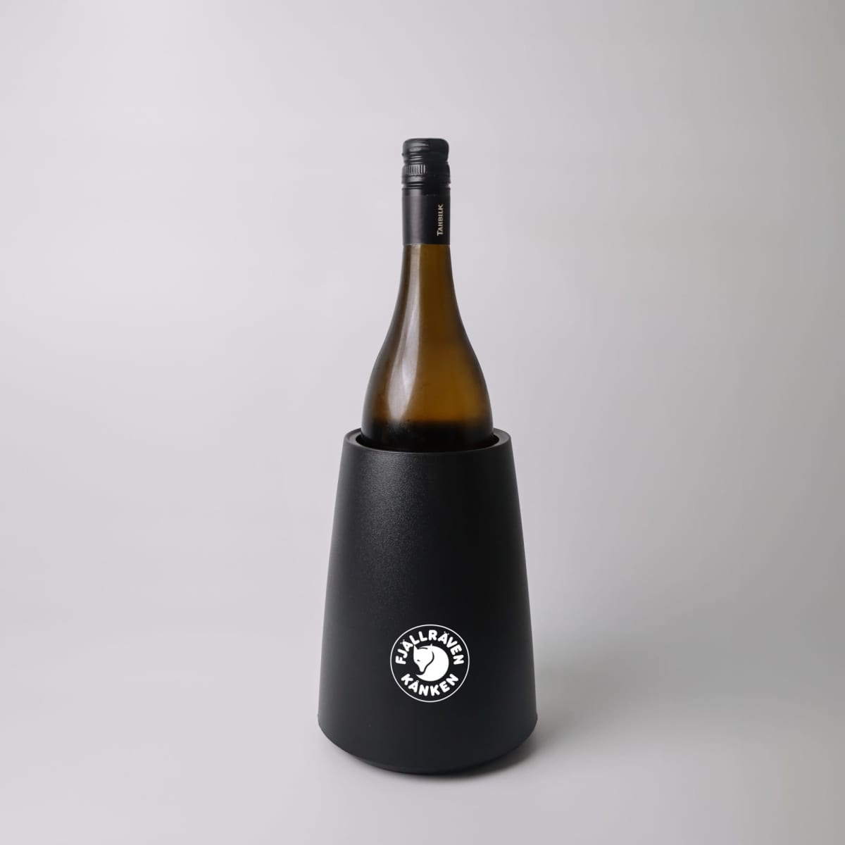 A wine bottle in a black Fjällräven wine cooler against a plain light background.
