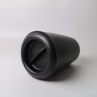 A black, cylindrical container with a twist lid, lying on its side against a white background.