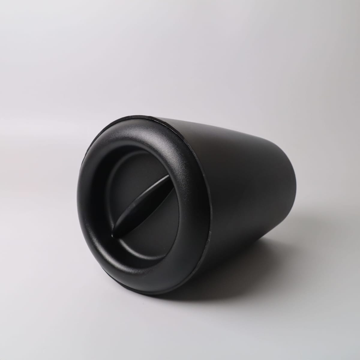 A black, cylindrical container with a twist lid, lying on its side against a white background.