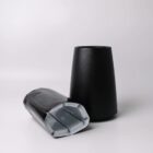 Two black, angular cups; one standing upright and one lying on its side on a white surface.