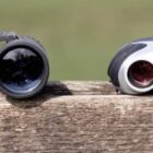 Three pairs of binoculars on a wooden surface with a blurred green background.