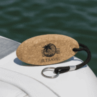 Cork keychain with JR Travel logo rests on a boat beside water.