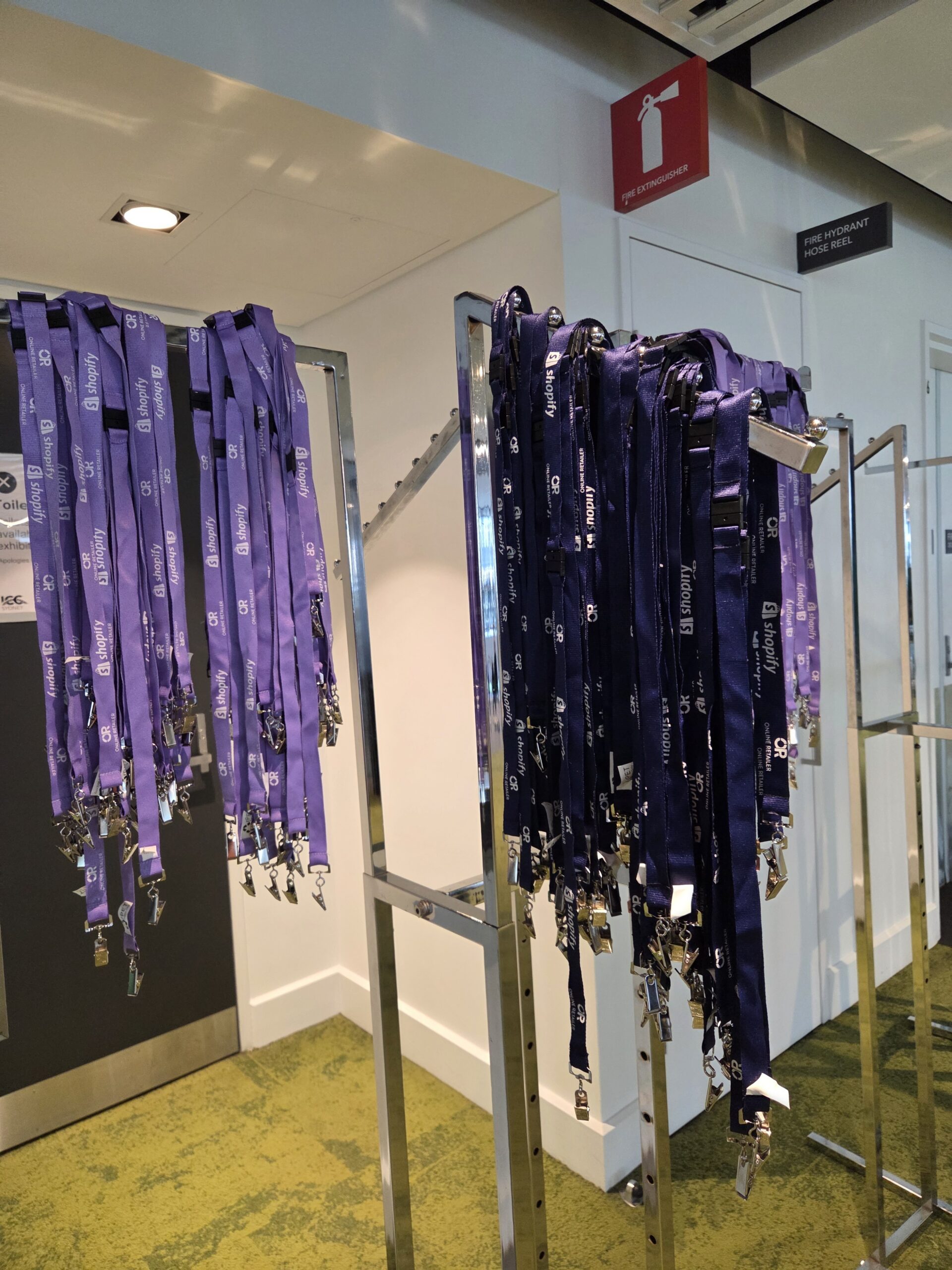 Rows of purple lanyards with name badges for Open Day hanging on racks at the event venue.