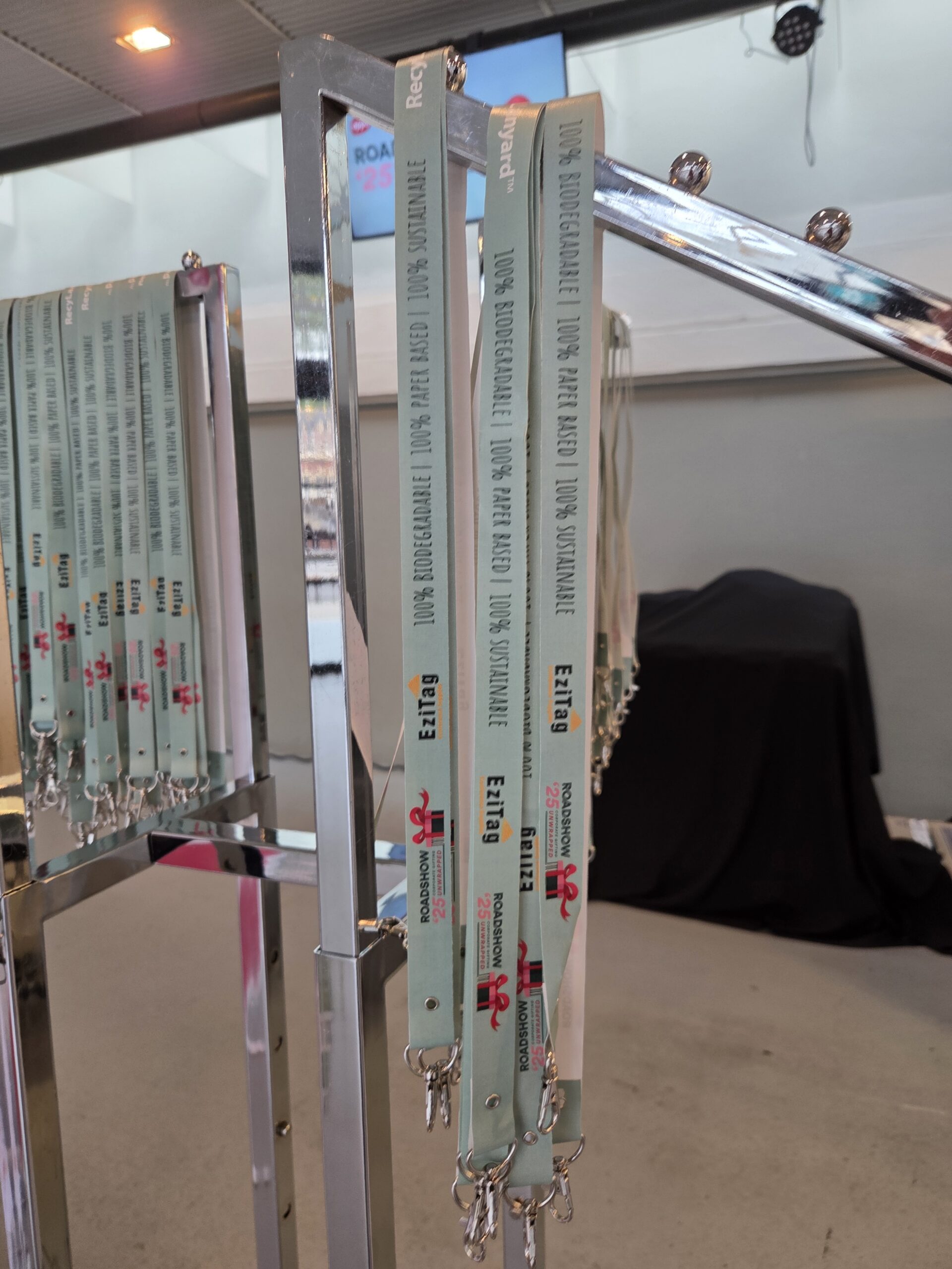 Light blue event lanyards, ideal for multi-day events, hang on a metal rack indoors.