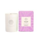 White candle in a jar next to a purple box labeled Tilley Sweet Berries & Musk.