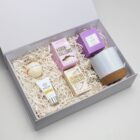 Gift box with marshmallows, drinking chocolate, candle, cup, soap, and hand cream.