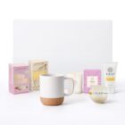 Gift set with a mug, candle, bath bomb, body lotion, marshmallows, and hot chocolate mix.