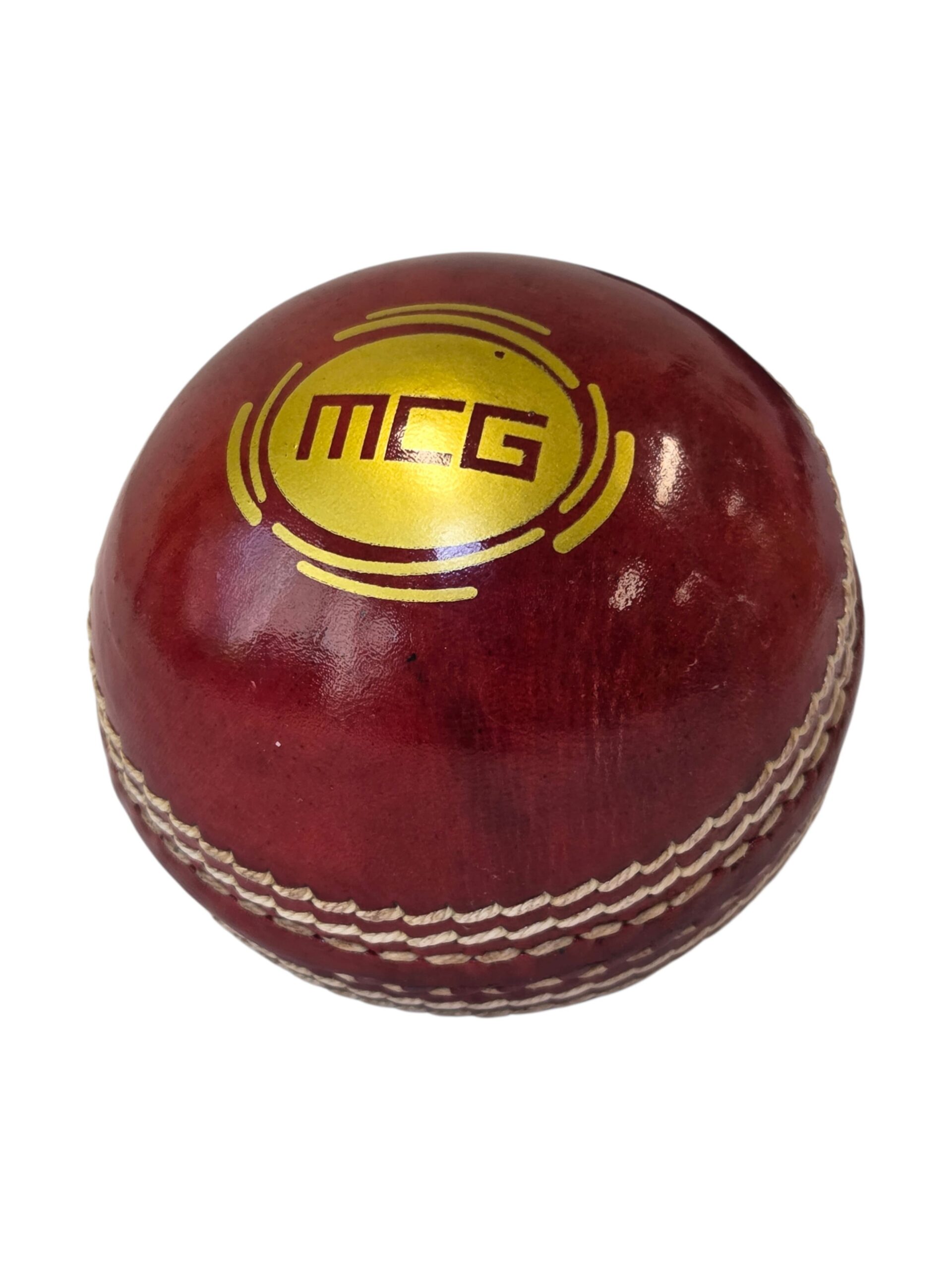 Red cricket ball with Melbourne Cricket logo and white stitching on a white background.