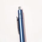 A blue retractable pen with a metal clip on a light background.