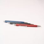 Four pens in blue, black, and red colors are arranged diagonally on a white surface.