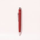 A red ballpoint pen with a silver tip and clip on a light pink background.