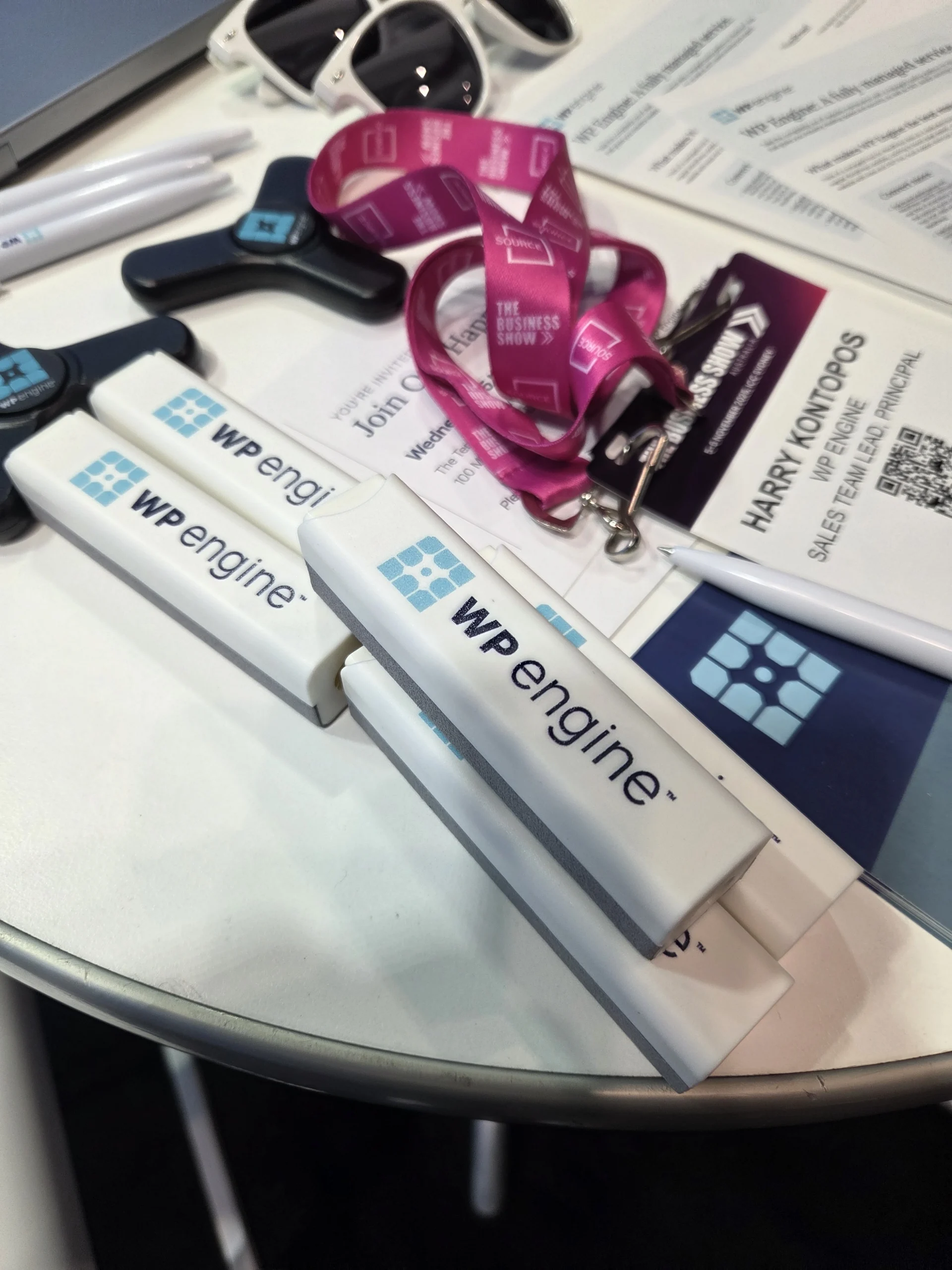 WP Engine branded items, conference badge, and logo file formats for printing on a white table.