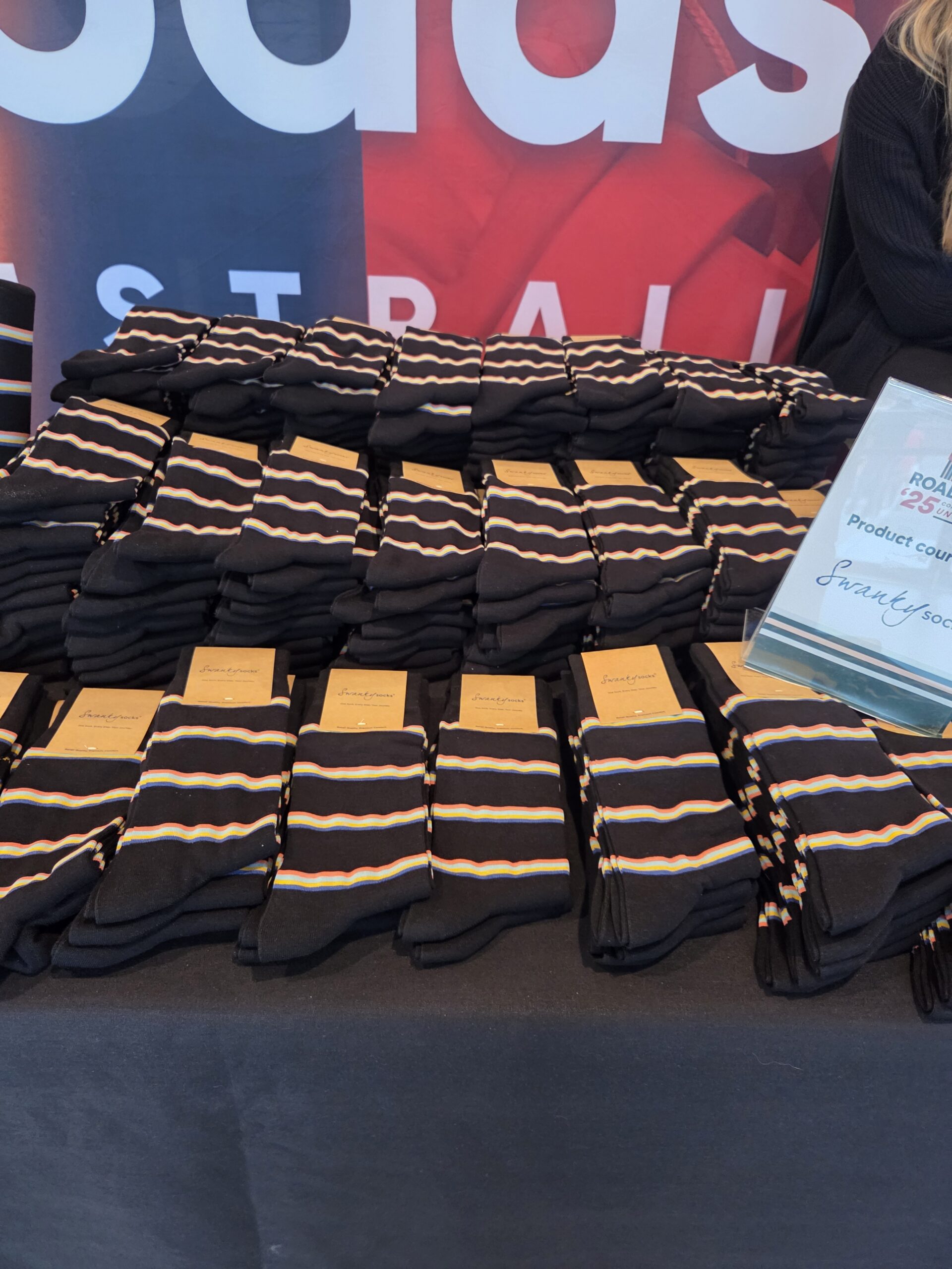 Stacks of black socks with white and yellow stripes, perfect for event merchandising displays.