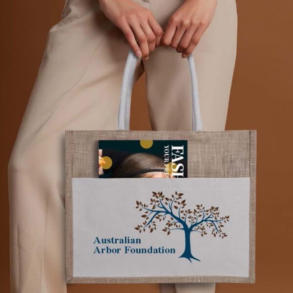 Person holding a tote bag with Australian Arbor Foundation logo and a magazine in the pocket.