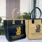 Two Ritz-Carlton Abu Dhabi tote bags, one black and one beige, side by side on a table.