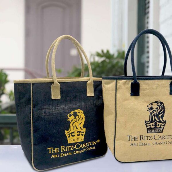 Two Ritz-Carlton Abu Dhabi tote bags with lion logos on an outdoor surface.