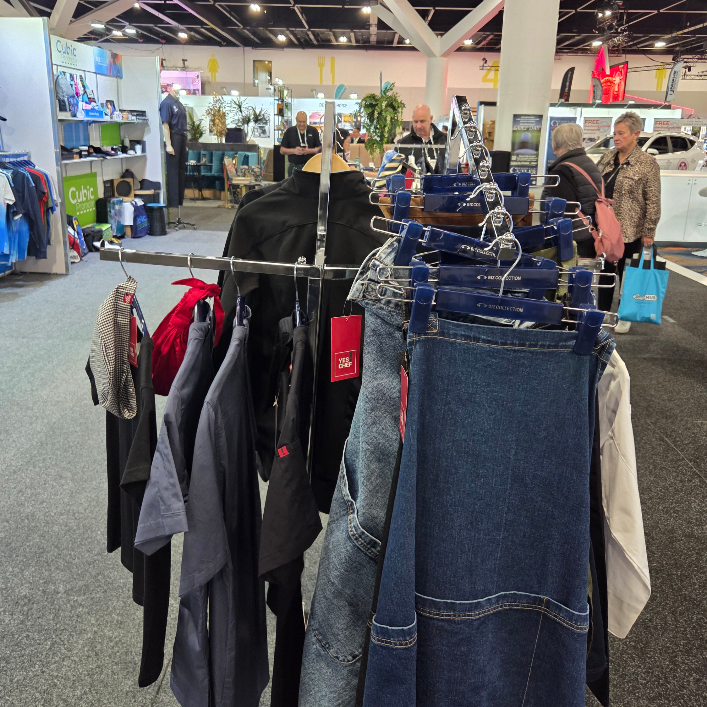Clothes hanging on a rack at an indoor market, showcasing products for trade shows.