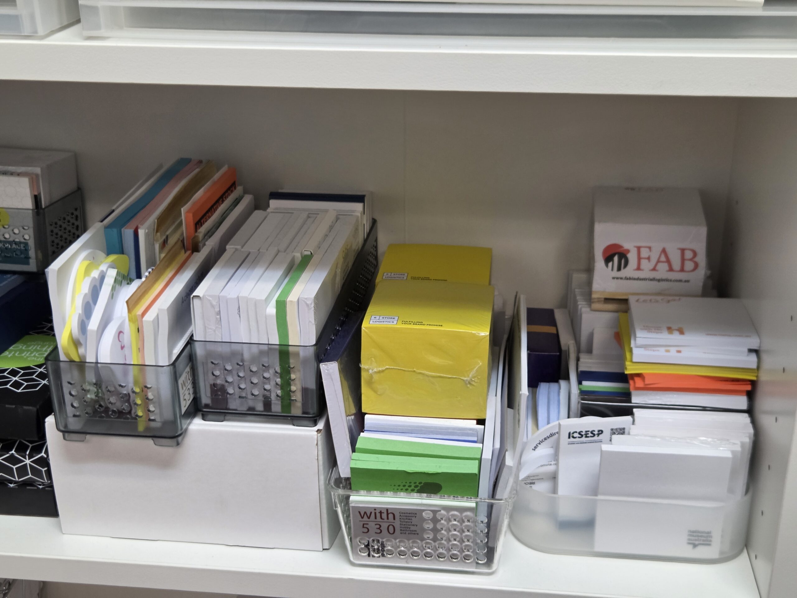 Organized shelf boosts brand recognition with colorful note cards in neat plastic containers.