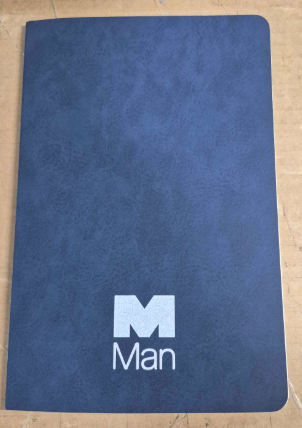A dark blue notebook with Man Group Australia printed in white on the cover.