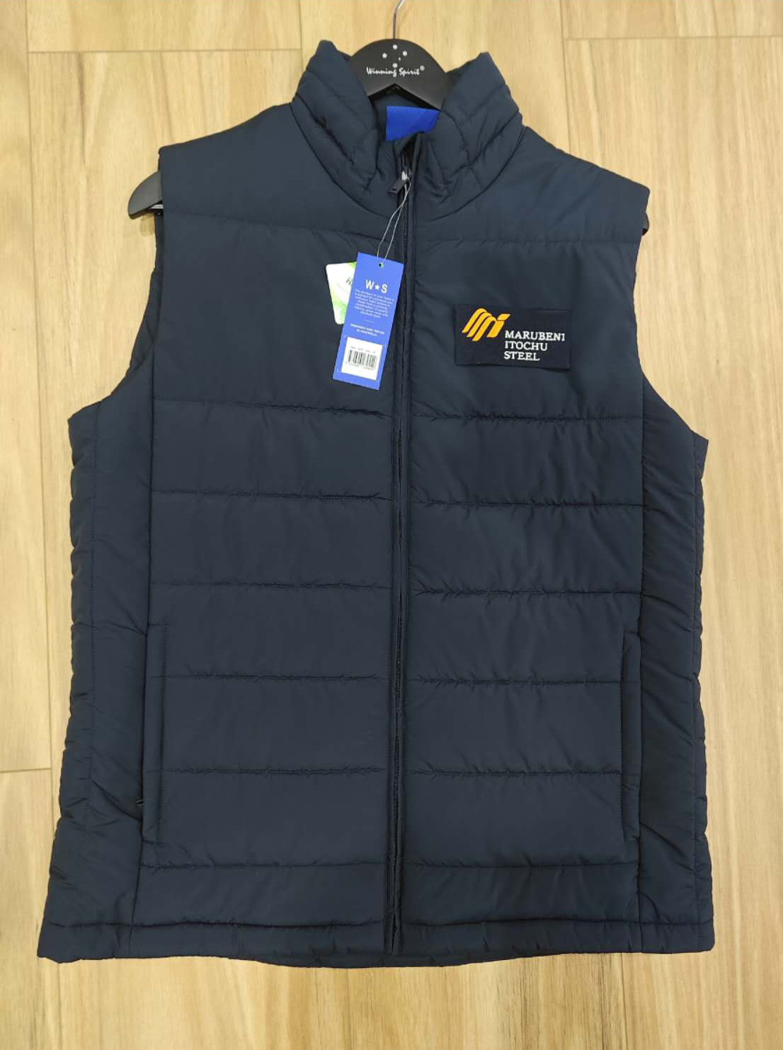 Navy blue puffer vest with tags and Marubeni-Itochu Steel logo on the chest.