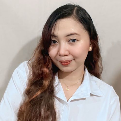 Meet the team: Woman with long wavy hair in a white shirt, smiling at the camera.