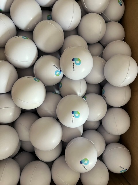 A box filled with white stress balls, some displaying the blue and green Prevento logo.