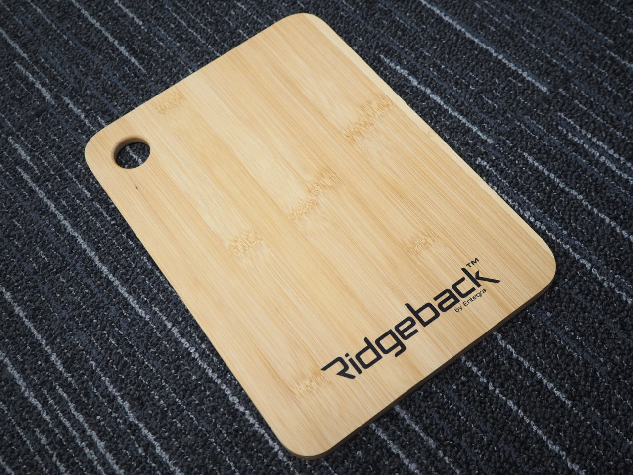 Rectangular bamboo products cutting board with Ridgeback logo, placed on a dark striped surface.