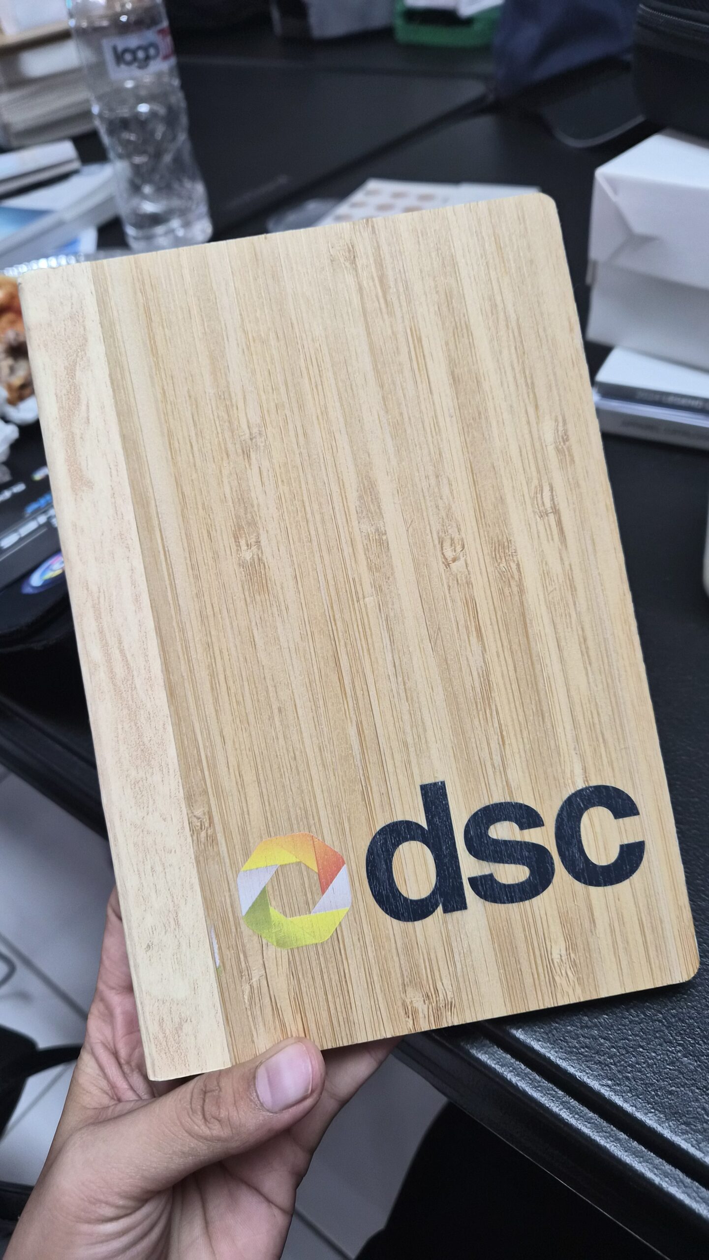 A hand holds a bamboo notebook with the dsc logo on the cover, showcasing bamboo products.