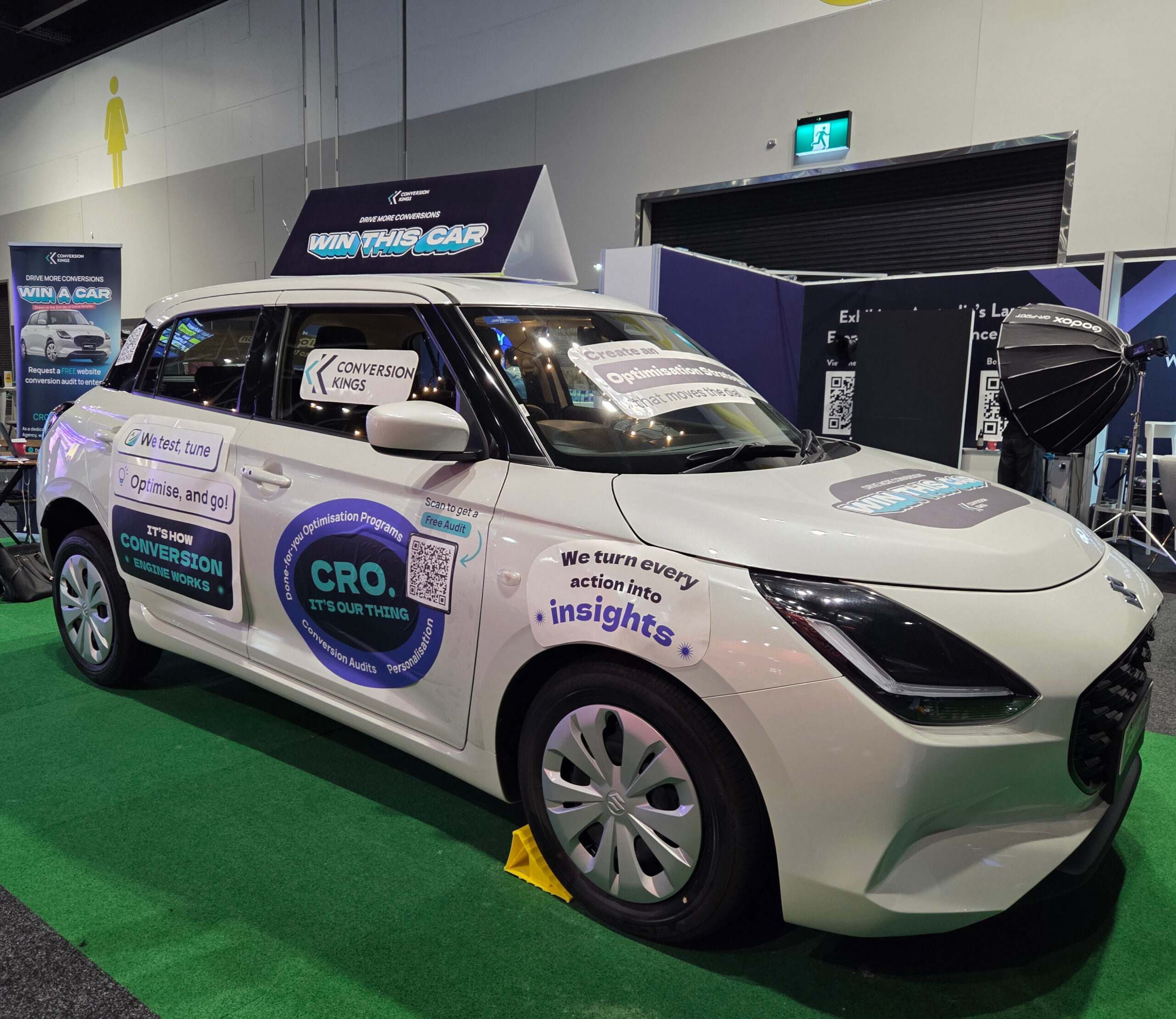 White car with marketing stickers at indoor expo, showcasing promotional products for tradeshows.