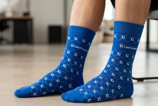 Person wearing blue LawConnect socks with a white geometric pattern, seated indoors in Sydney.