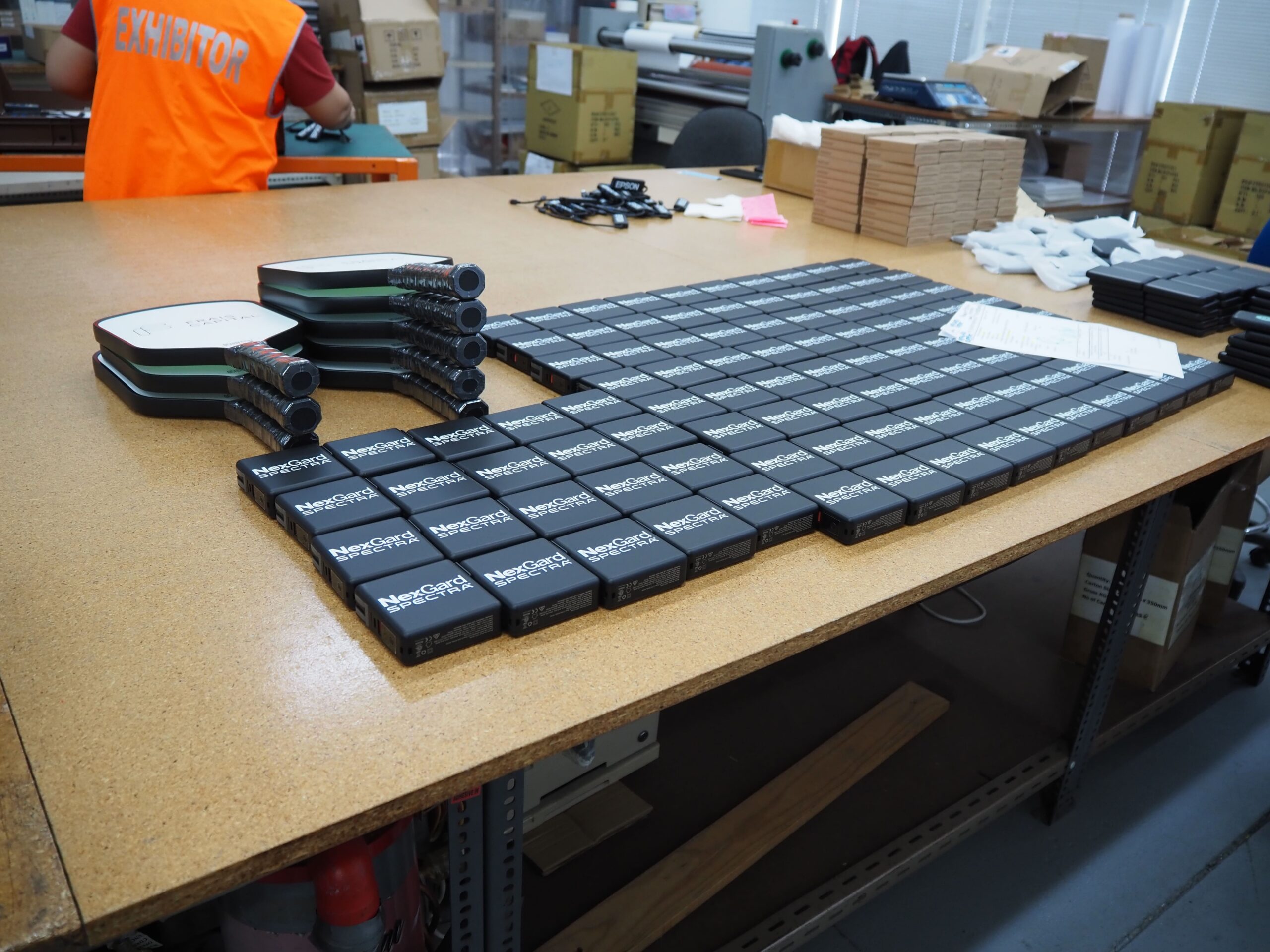 Dozens of black Network name badges, calculated for bulk orders, arranged on a workshop table.