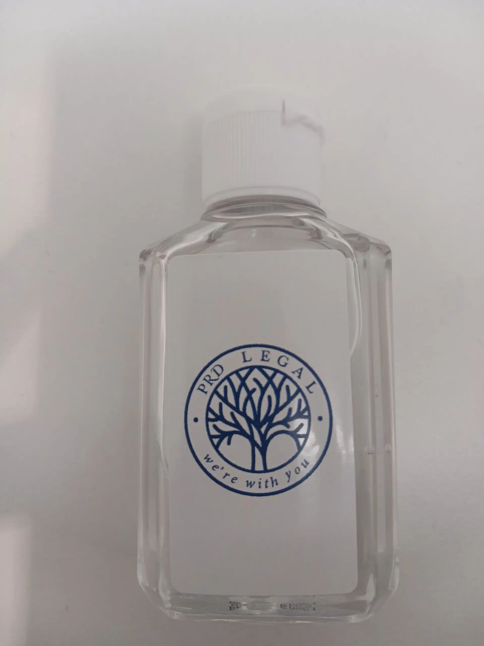 Clear bottle with white cap, PRD Legal label, blue tree logo—happy client approved.