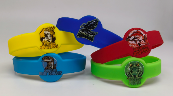 Four colorful wristbands with animal team logos from Kyneton High School: cockatoos, ravens, blue tongues, and frogs.