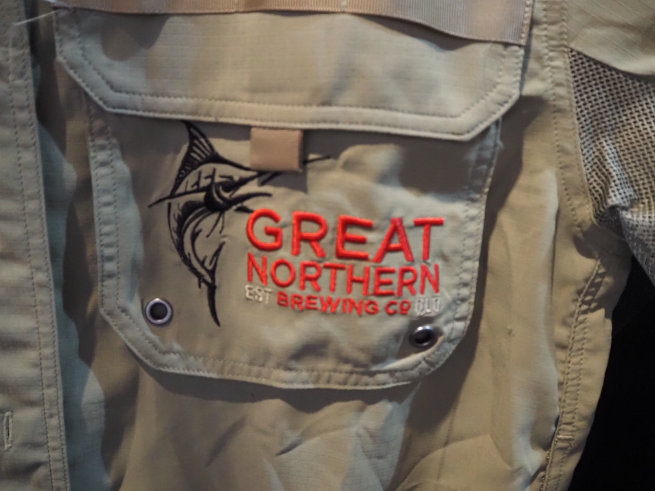Close-up of a jacket pocket with expert-recommended logo placement and a fish embroidery.