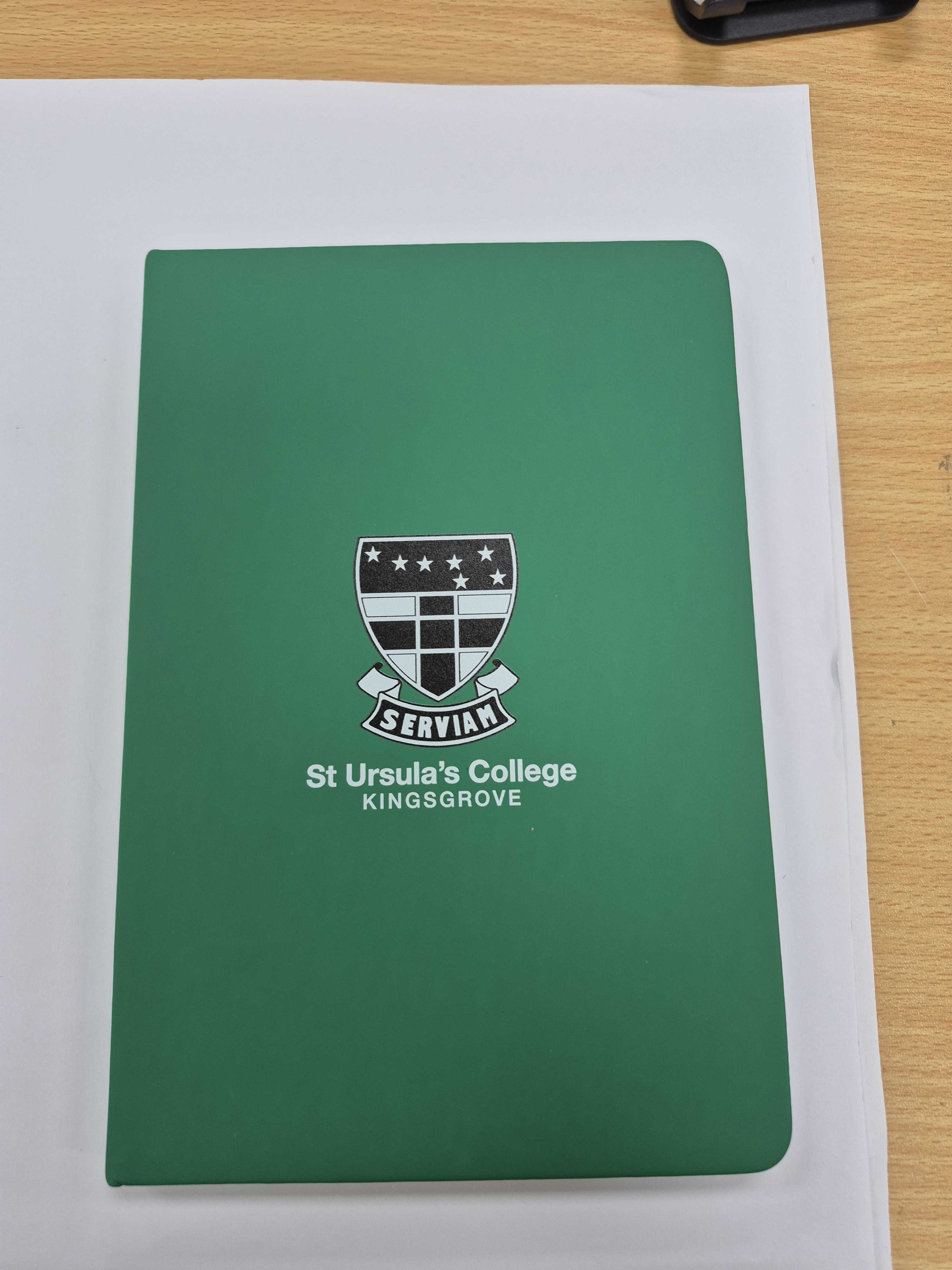 green notebook branded with St. Ursula's logo