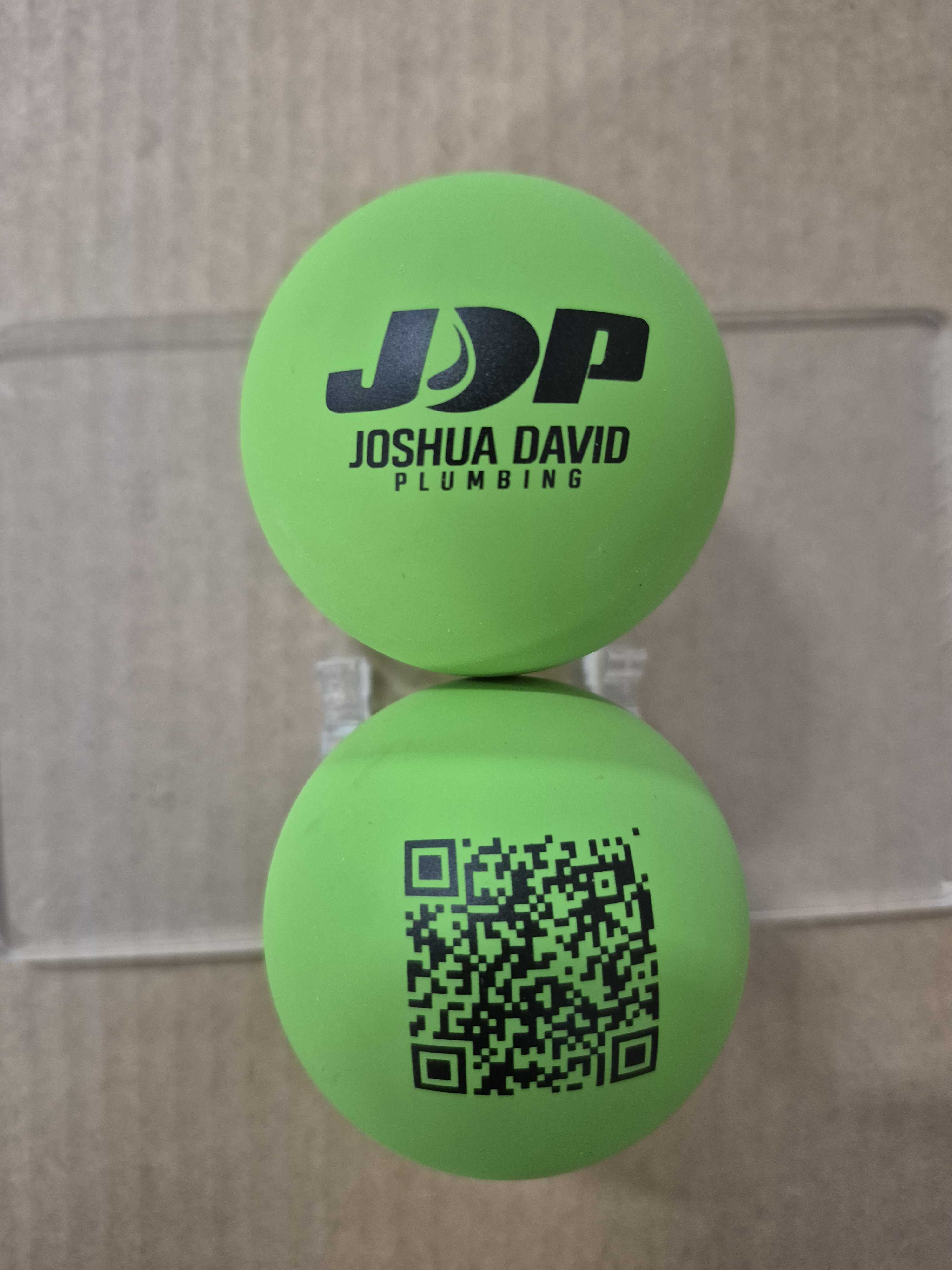 two green bounce balls printed with Joshua David plumbing logo and qr code