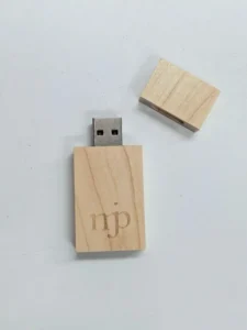 Wooden USB drive with magnetic cap removed showing USB connector and mjp monogram engraved on the body.