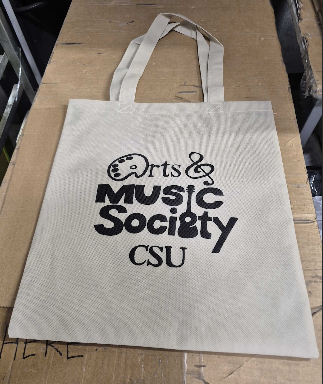 white tote bag with arts and music society csu logo